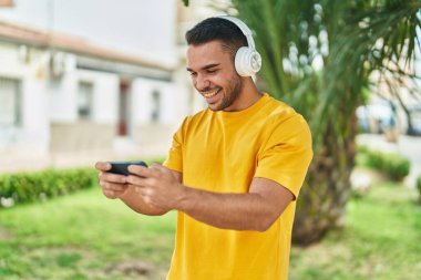 Parkta video oyunu oynayarak kendine güvenen İspanyol genç adam.