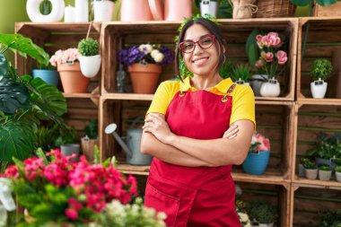 Çiçekçide kollarını kavuşturmuş duran kendine güvenen güzel bir Arap kadın çiçekçi.