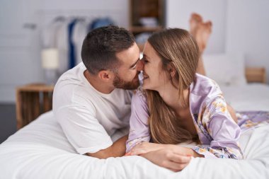 Man and woman couple lying on bed kissing at bedroom