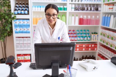 Genç Arap kadın eczacı. Eczanede bilgisayar kullandığından emin gülümsüyor.