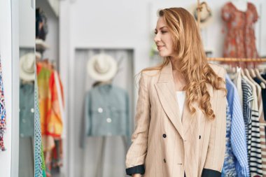 Young blonde woman customer wearing jacket at clothing store