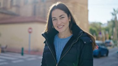 Sokakta kendine güvenen beyaz kadın gülümsüyor.