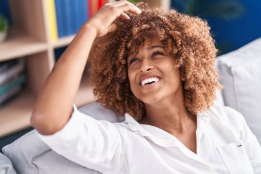 Afro-amerikalı bir kadın evdeki koltukta kendinden emin bir şekilde oturuyor.