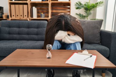 Young hispanic woman patient depressed having psychology session at clinic
