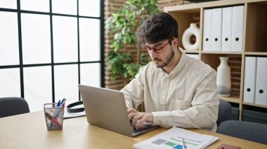 Young hispanic man business worker using laptop working at office