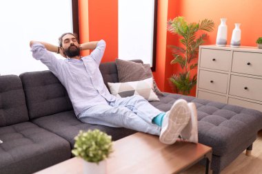 Genç İspanyol adam, ellerini başının üstüne koyup evinde kanepede oturarak rahatladı.