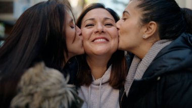Mother and daugthers kissing and hugging each other at street