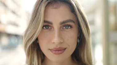 Sokakta ciddi bir ifadeyle duran genç sarışın kadın.