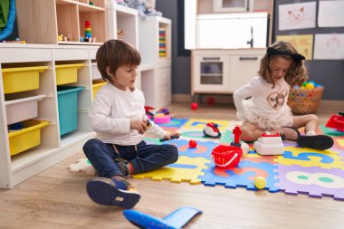 Süpermarket oyunu oynayan sevimli bir çocuk ve kız anaokulunun zemininde oturuyorlar.
