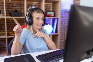 Video oyunları oynayan, kulaklık takan genç, beyaz bir kadın iki eliyle endişeli ve endişeli bir ifade takınıyor. 