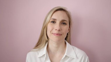 Young blonde woman smiling confident standing over isolated pink background