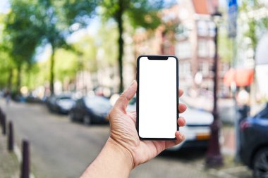 Elinde akıllı telefon tutan adam Amsterdam 'da beyaz boş ekran gösteriyor.