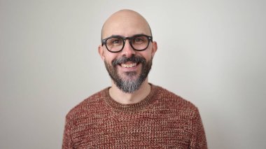 Genç kel adam, kendinden emin bir şekilde beyaz arka planda duruyor.