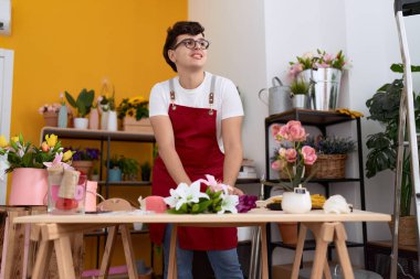 Non binary man florist make bouquet of flowers at flower shop