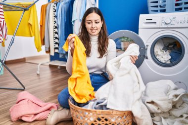 Genç, güzel İspanyol kadın gülümsüyor çamaşırhanede çamaşırları yıkayacak kadar kendinden emin.