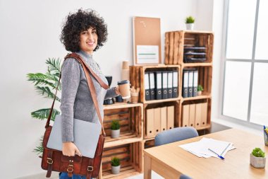 Young middle east woman business worker holding briefcase drinking coffee at office