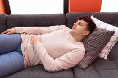 Non binary man lying on sofa sleeping at home