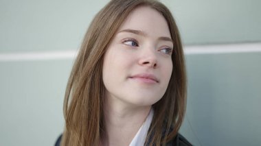 Sokakta ciddi bir ifadeyle yan tarafa bakan genç sarışın kadın.