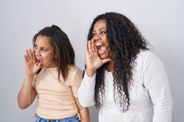 Anne ve küçük kızı beyaz arka planda durup el ele tutuşarak bağırıyor ve çığlık atıyorlar. iletişim konsepti. 