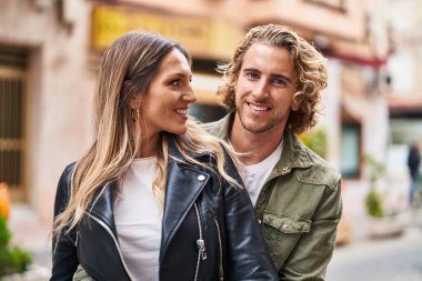 Kadın ve erkek gülümsüyor. Kendilerine güveniyorlar. Sokakta sarılıyorlar.