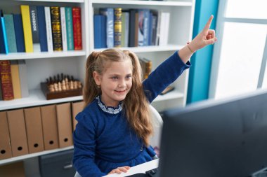 Sınıfta bilgisayar kullanan sevimli sarışın kız öğrenci.