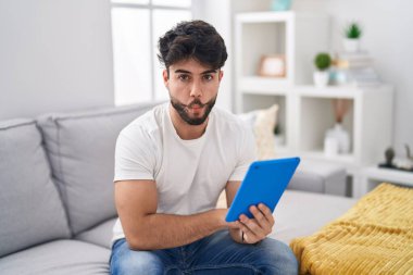 Kanepede oturan dokunmatik sakallı İspanyol adam dudaklarıyla balık suratı yapıyor, çılgınca ve komik bir jest. Komik ifade. 