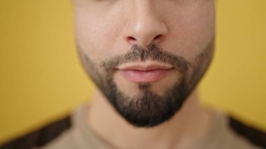 İzole edilmiş sarı arka planda gevşek bir suratı olan genç bir Arap.