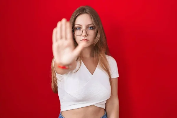 Młoda Biała Kobieta Stojąca Nad Czerwonym Tłem Przestaje Śpiewać Dłonią — Zdjęcie stockowe