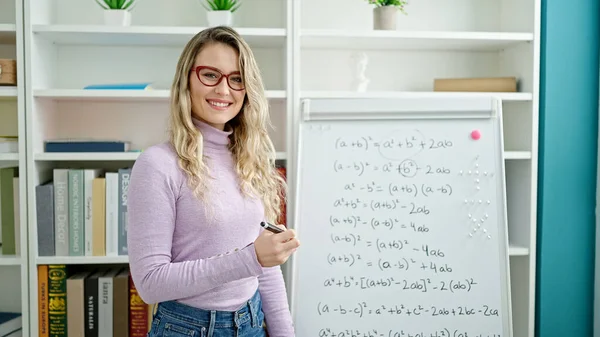 Young blonde woman teacher teaching maths lesson at classroom