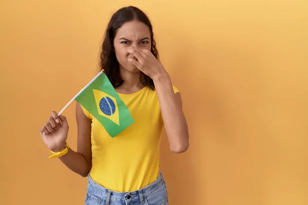 Mujer Hispana Joven Sosteniendo Bandera Brasil Oliendo Algo Apestoso Asqueroso — Foto de Stock