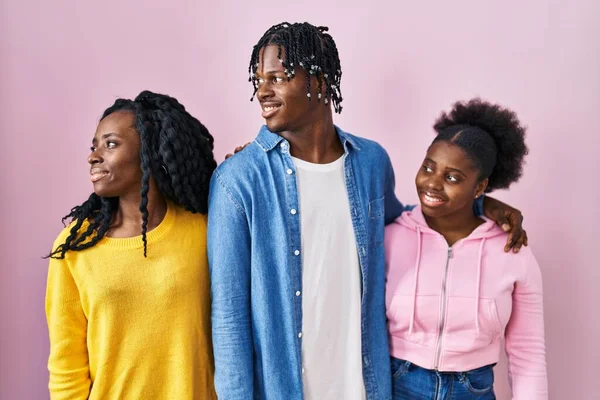 一组三个年轻的黑人站在粉红的背景上期待着侧面 以自然的面容和自信的微笑放松自己的姿态 — 图库照片