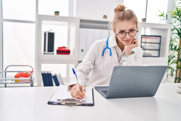 Young Blonde Woman Doctor Using Laptop Writing Medical Report Clinic — Fotografia de Stock