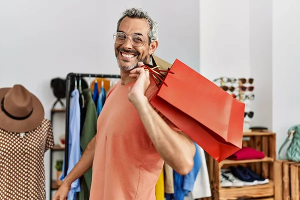 中年白髪男自信を持って笑みを浮かべてショッピングバッグで衣料品店 — ストック写真