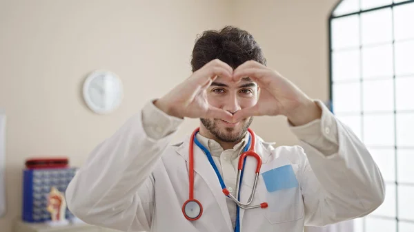 Молодой Латиноамериканец Доктор Улыбается Делая Сердечный Жест Руками Клинике — стоковое фото