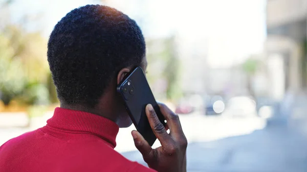 stock image African american woman talking on smartphone backwards at street