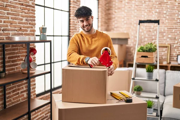 Young Hispanic Man Smiling Confident Packing Cardboard Box New Home — стоковое фото