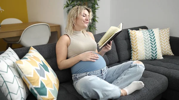 Jonge Zwangere Vrouw Lezen Boek Aanraken Buik Thuis — Stockfoto