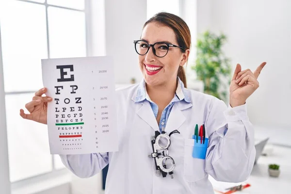 Ung Latinamerikansk Optiker Kvinna Som Håller Läkarundersökning Ler Glad Pekar — Stockfoto