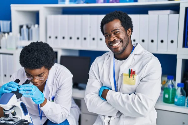 研究室で顕微鏡を使うアフリカ系アメリカ人男性と女性科学者 — ストック写真