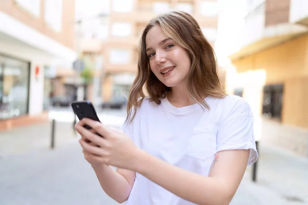 코카서스 여성은 거리에서 스마트폰을 사용하여 자신감 웃는다 — 스톡 사진