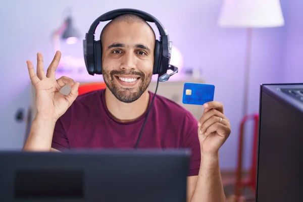 有胡子的西班牙男人用电脑上网购物 信用卡用手指签名 微笑友善的手势表示极好的象征 — 图库照片