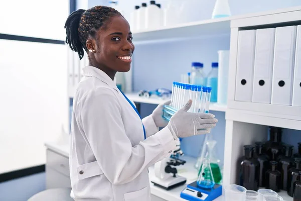 アフリカ系アメリカ人女性科学者の制服を着て実験室で試験管を保持 — ストック写真