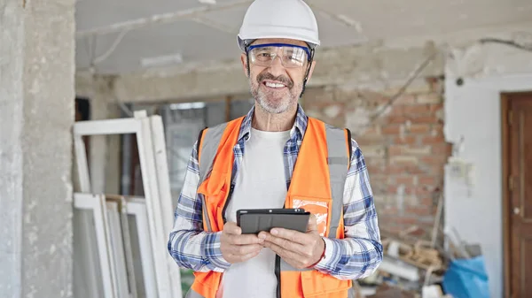 中年男子建筑工人微笑自信地使用触摸板在建筑工地 — 图库照片
