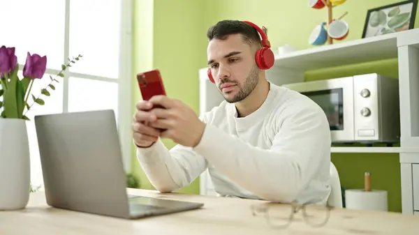 Joven Hombre Hispano Usando Smartphone Auriculares Sentados Mesa Comedor —  Fotos de Stock