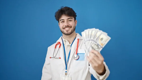 Joven Médico Hispano Sonriendo Confiado Sosteniendo Dólares Sobre Fondo Azul — Foto de Stock