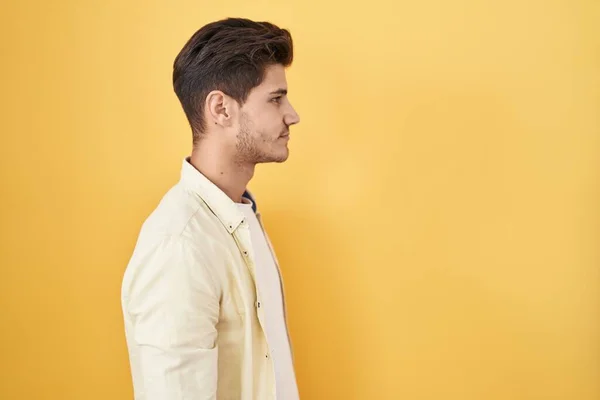 Sarı Arka Planda Dikilen Spanyol Genç Adam Yan Bakıyor Rahat — Stok fotoğraf