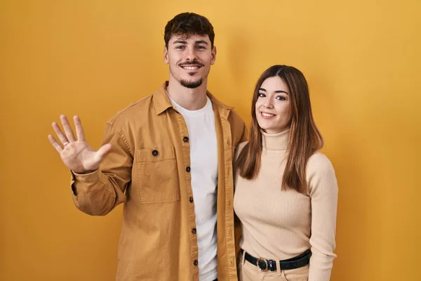 Jong Hispanic Paar Staande Gele Achtergrond Tonen Wijzen Met Vingers — Stockfoto
