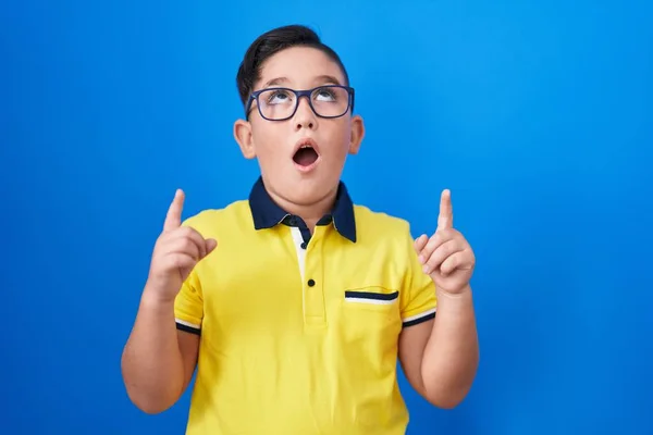 Jovem Criança Hispânica Sobre Fundo Azul Espantado Surpreso Olhando Para — Fotografia de Stock