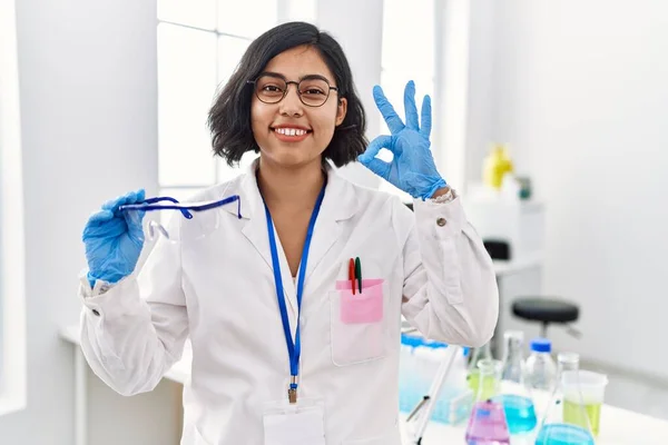 Joven Mujer Hispana Trabajando Laboratorio Científico Sosteniendo Gafas Seguridad Haciendo —  Fotos de Stock