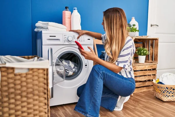 Junge Blonde Frau Benutzt Smartphone Und Wäscht Wäsche Waschküche — Stockfoto